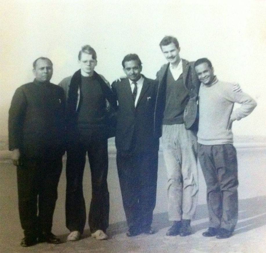 Five men standing together on a beach