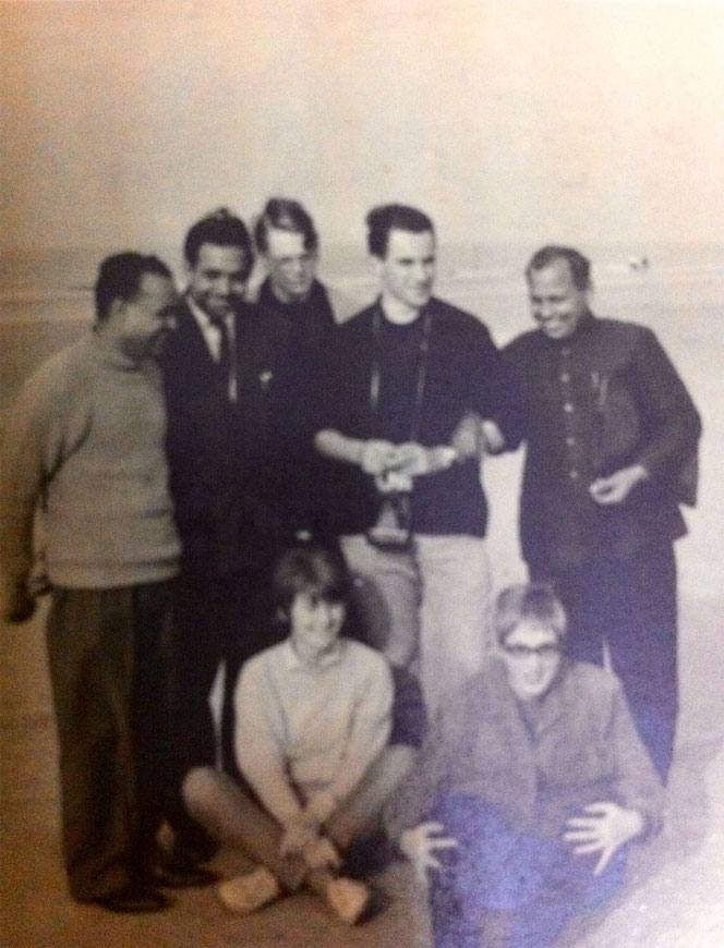 A group of friends on a beach, two of them seated in front